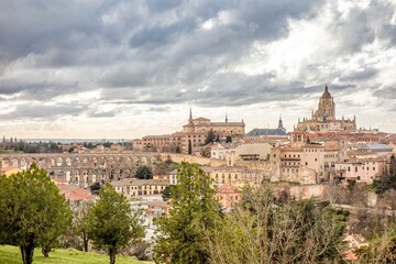 Panoramic view of Segovia from which we can see the Cathedral and the famous aqueduct of the city with a cloudy sky on a winter sunset