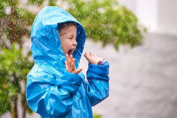 Young girl, rain and playing outside in winter, raincoat and playful in the water. Joyful, laughing and happy child in cold weather and raindrops, screaming toddler and excited in backyard of home - obrazy, fototapety, plakaty