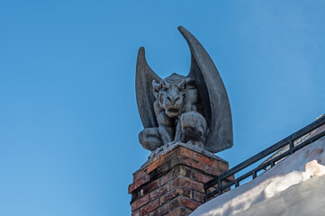 Gypsum Gargoyle sits on the roof against the blue sky.