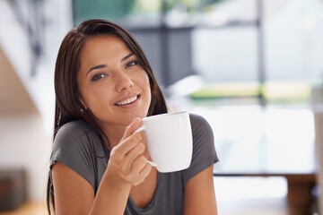 Portrait, coffee and relax with woman in kitchen of home to relax in morning or on weekend time off. Face, smile and mug with happy young person drinking tea in apartment for peace or wellness