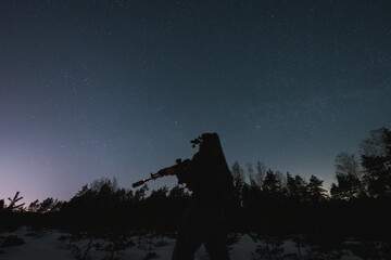 A soldier with a nightvision device and a rifle with a silencer and laser sight against the...