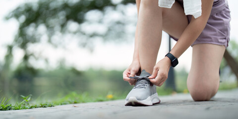 Woman tying shoe laces. Closeup of female sport fitness runner getting ready for jogging outdoors on park