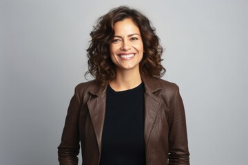 Portrait of a smiling woman in brown leather jacket over grey background