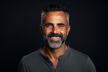 Portrait of a happy mature man smiling at camera against black background