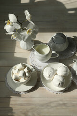 Spring breakfast with marshmallow, coffee and milk. Flatlay with food and flower in white color