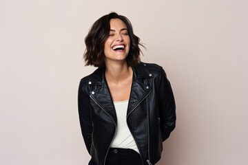 Portrait of a laughing young woman in a leather jacket on a light background