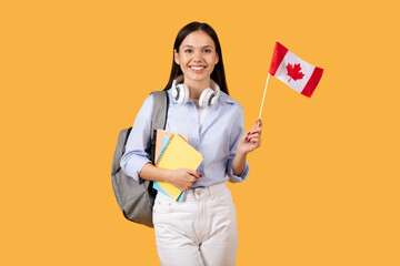 Happy lady student with Canadian flag and headphones holds notebooks