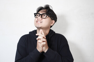 Adult Asian man showing thinking gesture with his eyes looking up.