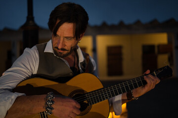 Close-up of a professional guitarist in a waistcoat playing the Spanish guitar. The man is giving a...