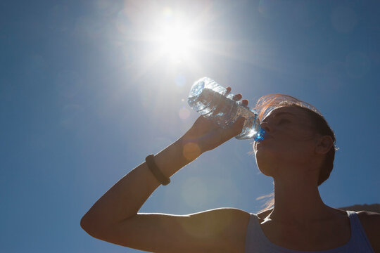 Woman Drinking Water from Bottle against Blue Sky
