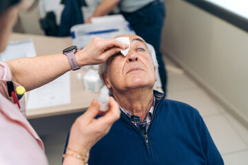 Applying eye drops to a senior before non-invasive glaucoma laser treatment.