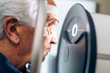 Elderly patient receives a glaucoma screening using a laser eye scanner.