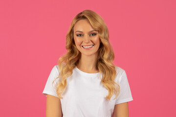 Beautiful blonde lady posing for portrait on pink studio background