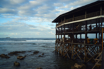 Wooden bungalow with terrace on piles on the sea beach.