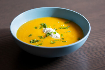delicious carrot soup in a bowl with cream and green onion close-up
