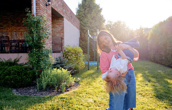Young woman holding toddler son in their home backyard.