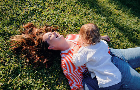 Young woman playing with her small son on the green grass
