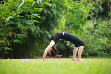 Chinese woman practicing yoga outdoors.