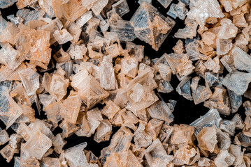 Pink Himalayan salt crystals  in different shapes close up with black background.