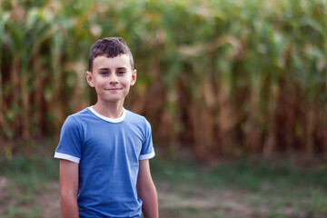 Happy boy standing near a corn field