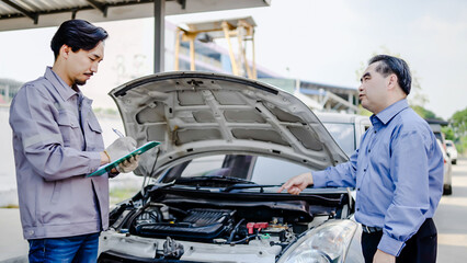 Young asian mechanic man show the car report on a data file to client at the roadside, A mechanic...