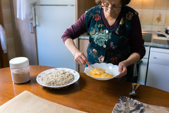 Senior woman beating eggs to coat the croquettes