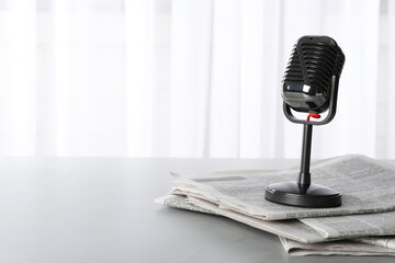 Newspapers and vintage microphone on grey table, space for text. Journalist's work - obrazy, fototapety, plakaty