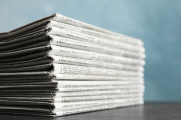 Stack of newspapers on blue background, closeup. Journalist's work