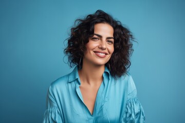 Portrait of beautiful smiling woman in blue shirt on blue background.