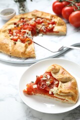 Tasty galette with tomato and cheese (Caprese galette) on white marble table, closeup