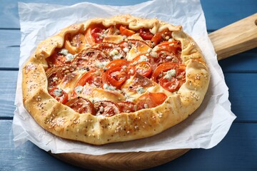 Tasty galette with tomato and cheese (Caprese galette) on blue wooden table, closeup