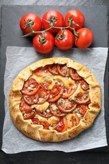 Tasty galette with tomato and cheese (Caprese galette) on dark table, top view