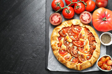 Tasty galette with tomato and cheese (Caprese galette) on dark textured table, top view. Space for text