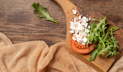 Close-up of rucolla cottage cheese and tomato on a wooden board. Healthy vegetarian breakfast. Top view