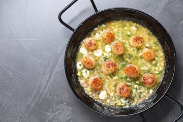 Fried scallops with sauce in dish on grey table, top view. Space for text