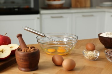 Fototapeta na wymiar Cooking process. Metal whisk, bowl and products on wooden table in kitchen