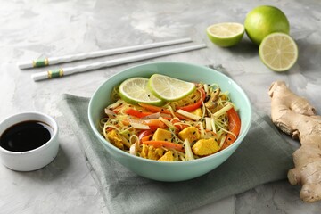 Stir-fry. Delicious cooked noodles with chicken and vegetables in bowl served on gray textured table