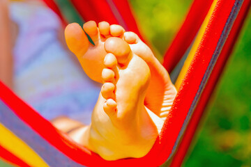 Close up young beautiful girl sleeping in a hammock with bare feet, relaxing and enjoying a lovely...