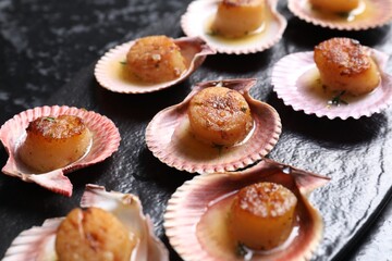 Delicious fried scallops in shells on black table, closeup
