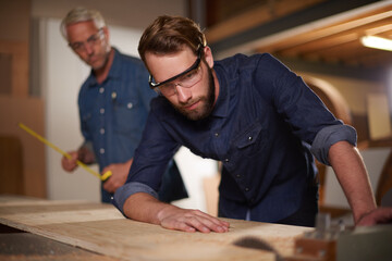 Carpenter, team and man with wood saw for planning construction project or senior father teaching...