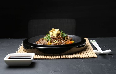 Stir-fry. Tasty noodles with meat and vegetables served on dark textured table