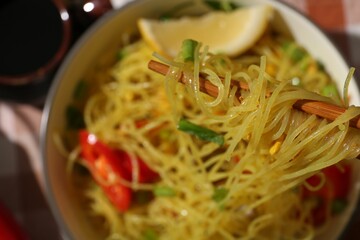 Stir-fry. Eating tasty noodles with chopsticks at table, closeup and space for text