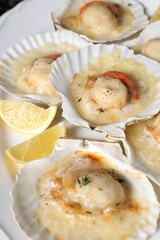 Fried scallops in shells and lemon on plate, closeup