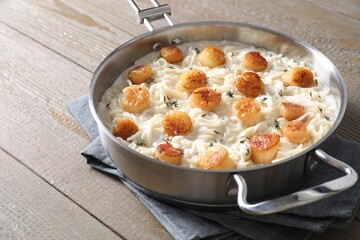 Delicious scallop pasta in pan on wooden table, closeup
