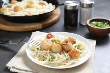Delicious scallop pasta with green onion served on grey table