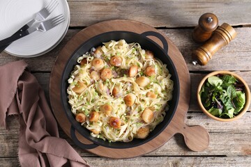 Delicious scallop pasta with onion served on wooden table, flat lay
