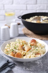 Delicious scallop pasta with spices in bowl on gray textured table