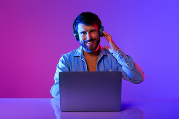 Guy using technology working on laptop wearing headset in studio