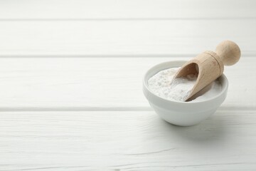 Baking powder in bowl and scoop on white wooden table, space for text