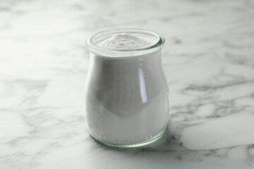 Baking powder in jar on white marble table
